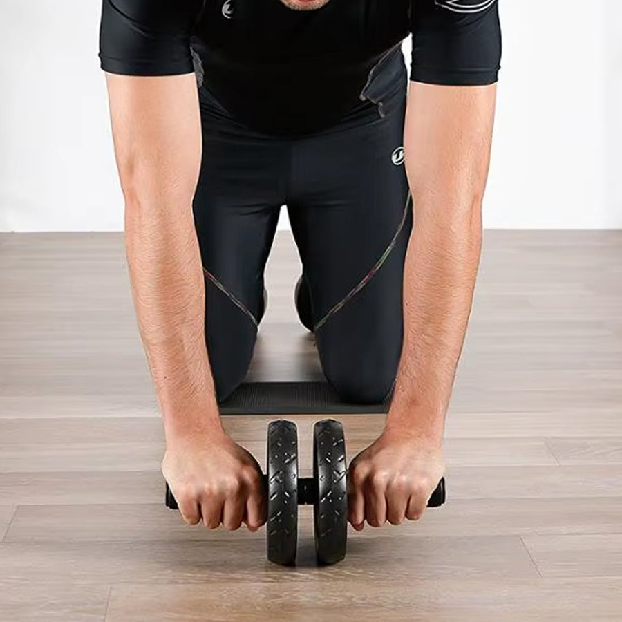 Person using a black exercise roller on a wooden floor.