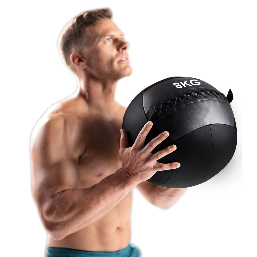 Man holding a 8kg black medicine ball on a white background