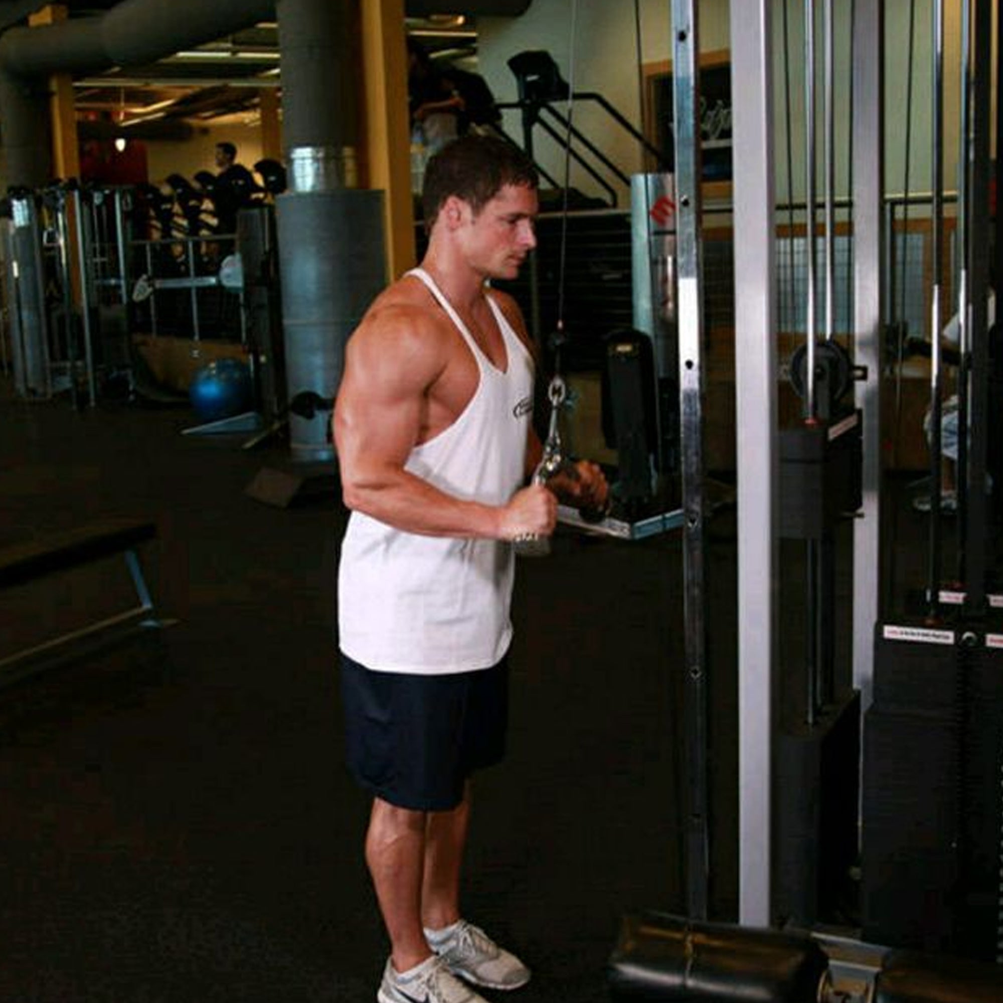 Man exercising in a gym using a cable machine.