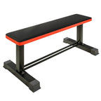 A flat weight bench with a black pad, red edges, and a steel frame designed for strength training exercises like bench press and dumbbell workouts.