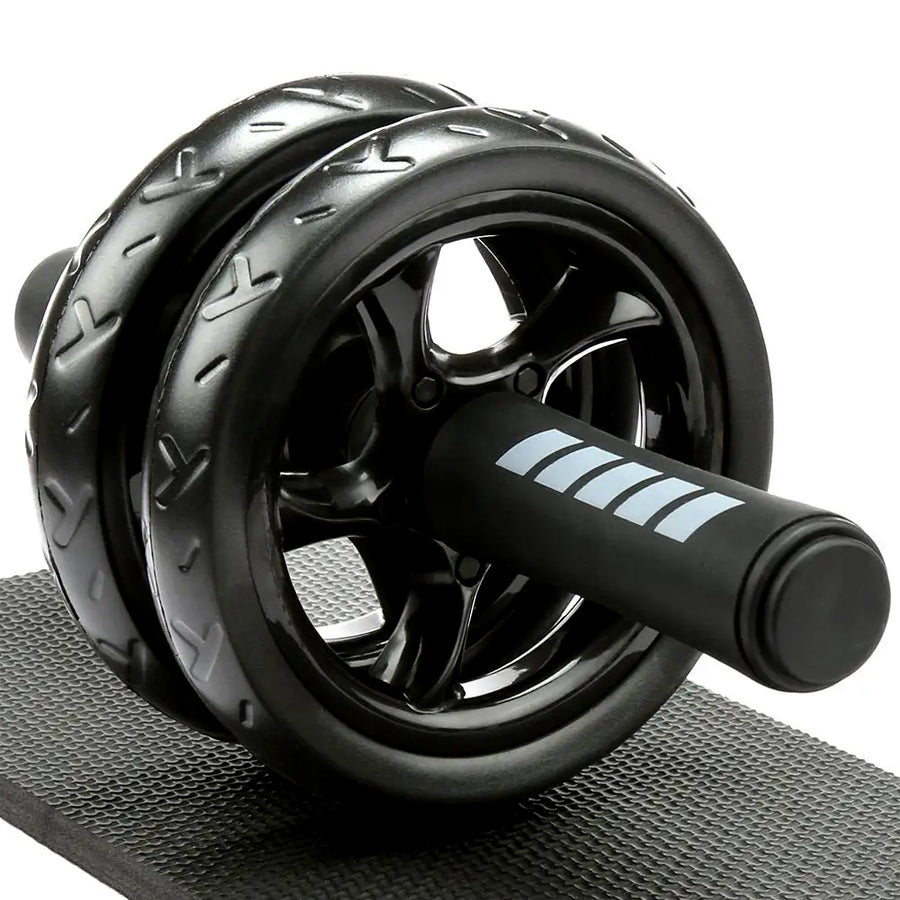 A black double-wheel ab roller with ergonomic handles and a high-density knee pad, placed on a textured surface.