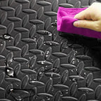Person cleaning a textured black surface with a purple cloth