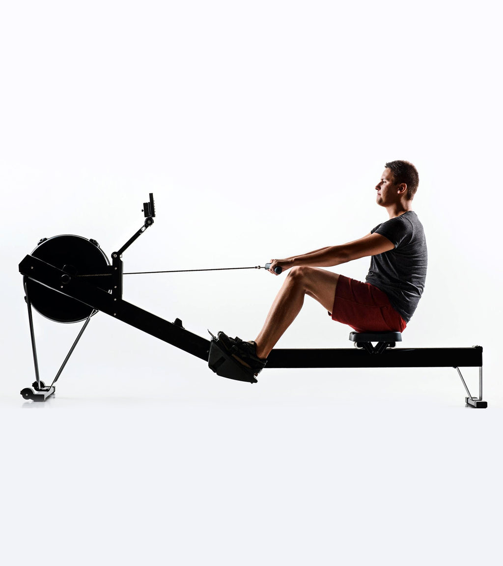 Person using a rowing machine on a white background