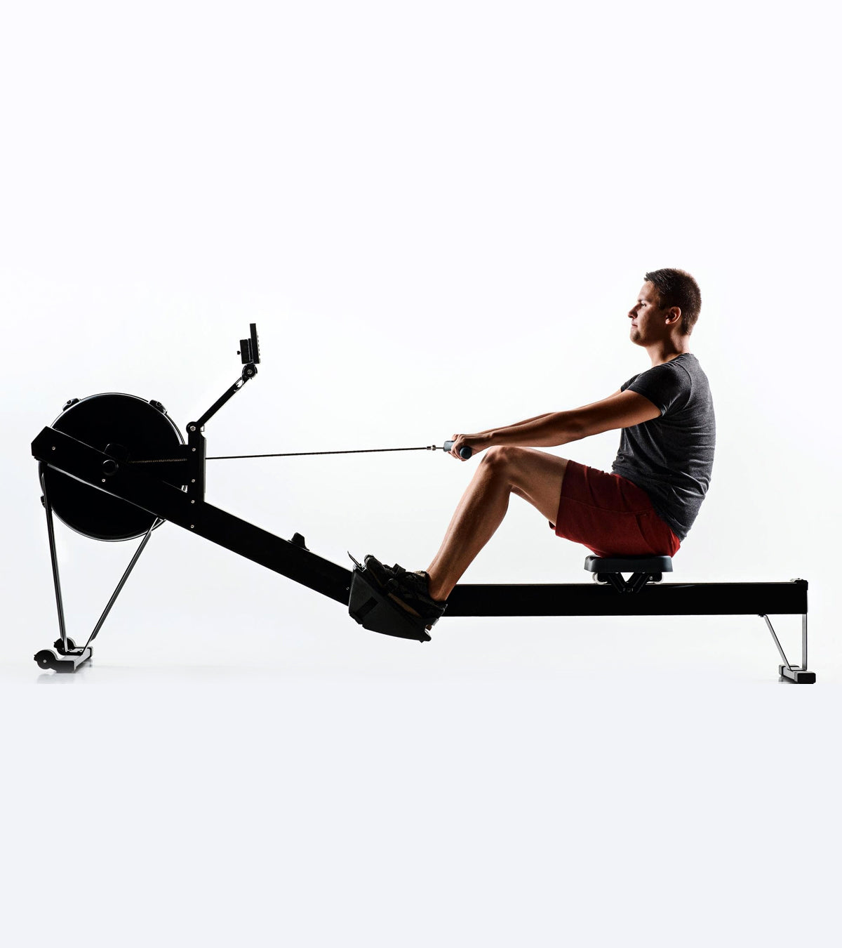 Person using a rowing machine on a white background
