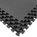 Interlocking black EVA foam tiles with a puzzle-like design, showing shock absorption and non-slip surface texture.