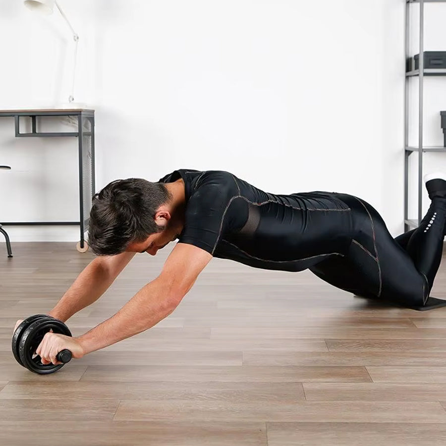 Man doing push-ups with a black ab roller in a home setting.