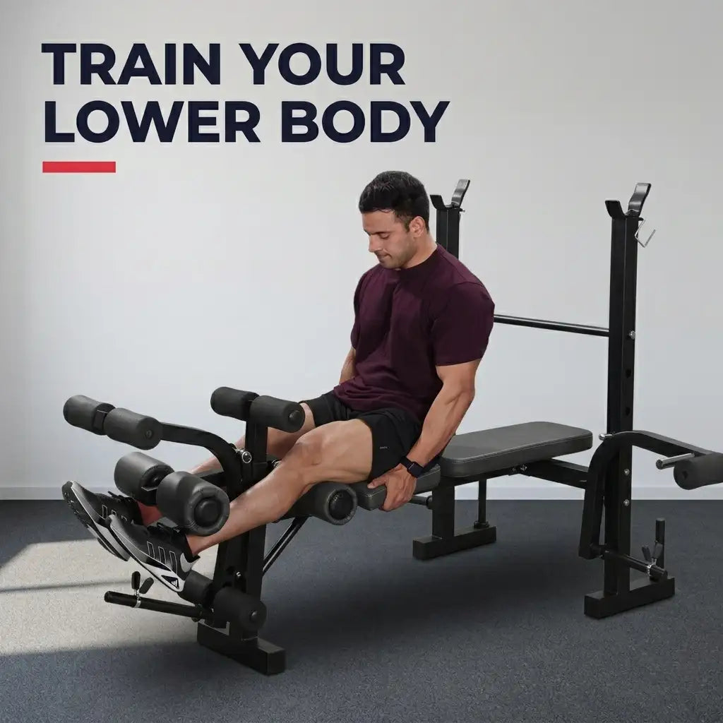 A man sits on a black leg extension gym machine in a minimalist gray room, wearing a dark maroon t-shirt and black shorts. The text 'TRAIN YOUR LOWER BODY' is displayed in the upper left corner.
