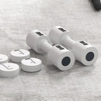 Set of white dumbbells with black weight plates on a gray surface