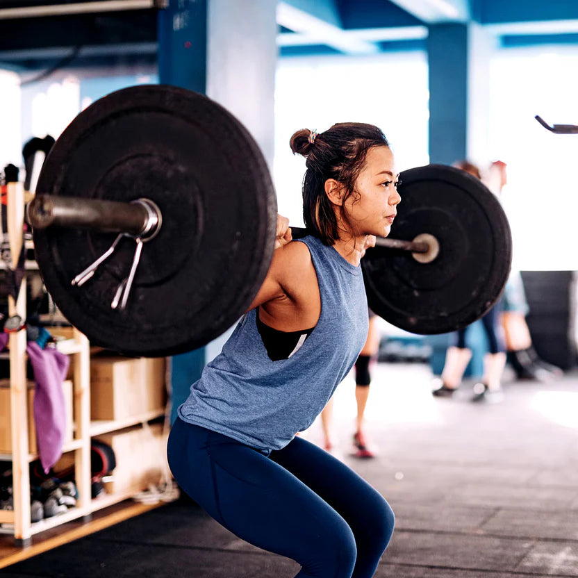 Woman lifting a barbell in a gym setting