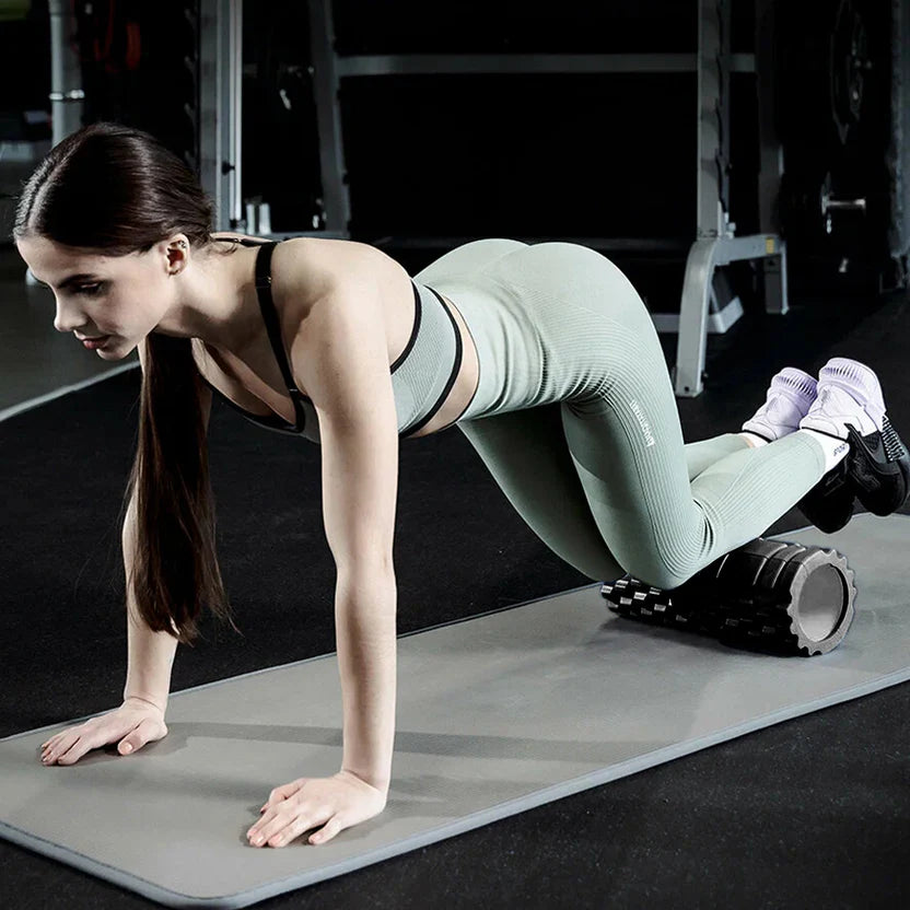 Woman in green athletic wear performing a exercise on a mat in a gym.