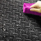 Person cleaning a textured black surface with a pink cloth