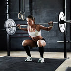 Woman performing a squat with a barbell in a gym setting