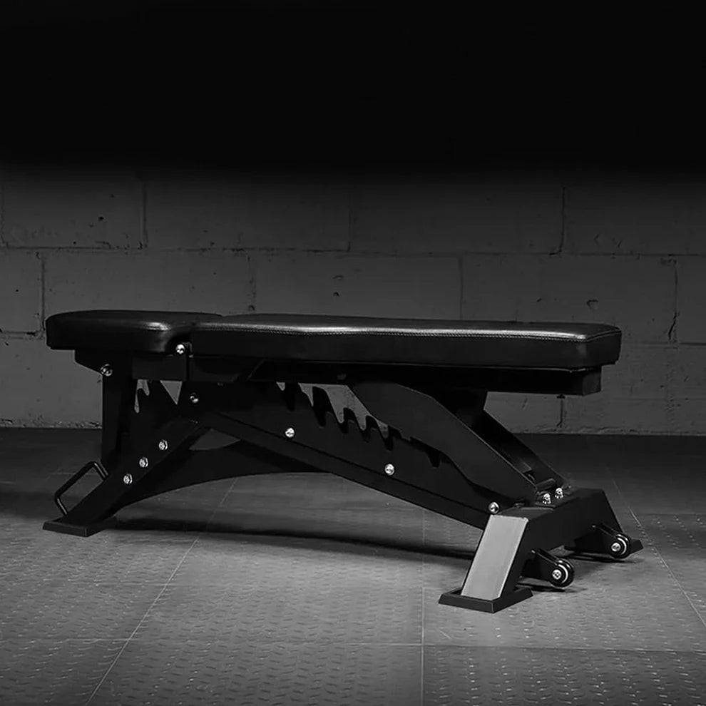 Black adjustable weight bench on a dark floor with a gray wall background