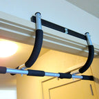 Doorway pull-up bar attached to a ceiling with a door in the background.